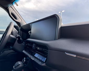 May include: A black car interior with a large touchscreen display, a steering wheel, and a gear shifter. The dashboard is made of black leather and has a silver trim.