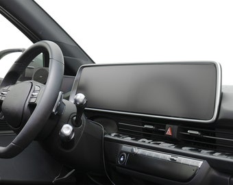 May include: A black car interior with a steering wheel, a gear shifter, and a large touchscreen display.