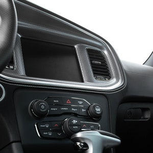 May include: A black car interior with a black leather steering wheel, a black dashboard with a touchscreen display, and a black center console with buttons and controls.