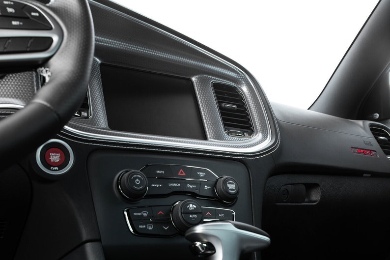 May include: A black car interior with a black leather steering wheel, a black dashboard with a touchscreen display, and a black center console with buttons and controls.