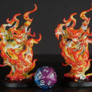 May include: Two miniature fire elementals painted in shades of red, orange, and yellow. The elementals are posed in a dynamic, fiery stance.