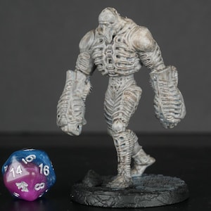 May include: A white painted miniature figure of a skeletal humanoid with large, clawed hands. The figure is standing on a black base with a gray, textured surface.