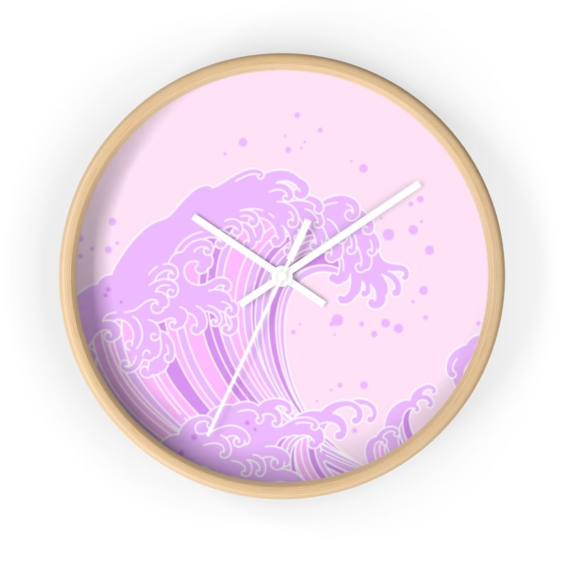 May include: A pink and white wall clock with a design of a large wave in a Japanese style. The wave is outlined in white and filled with shades of purple.
