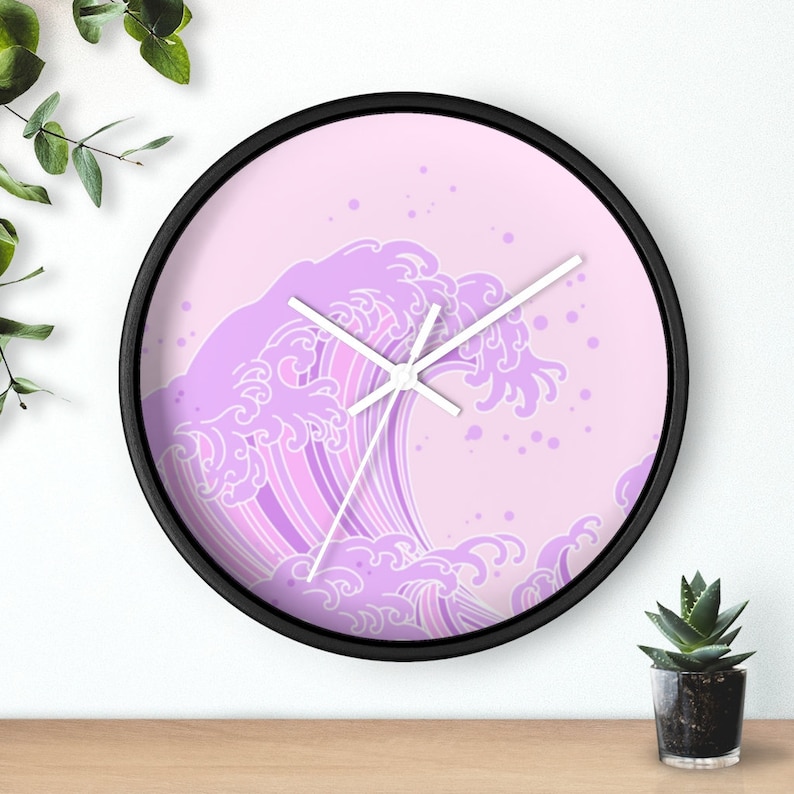 May include: A pink and white clock with a wave design. The clock has a black frame and white hands.
