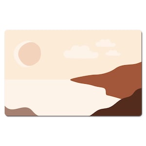May include: A rectangular desk mat featuring a minimalist landscape design. The artwork depicts a beige sky with a light brown sun and three white clouds. Below, a beige sea meets brown and dark brown landforms.