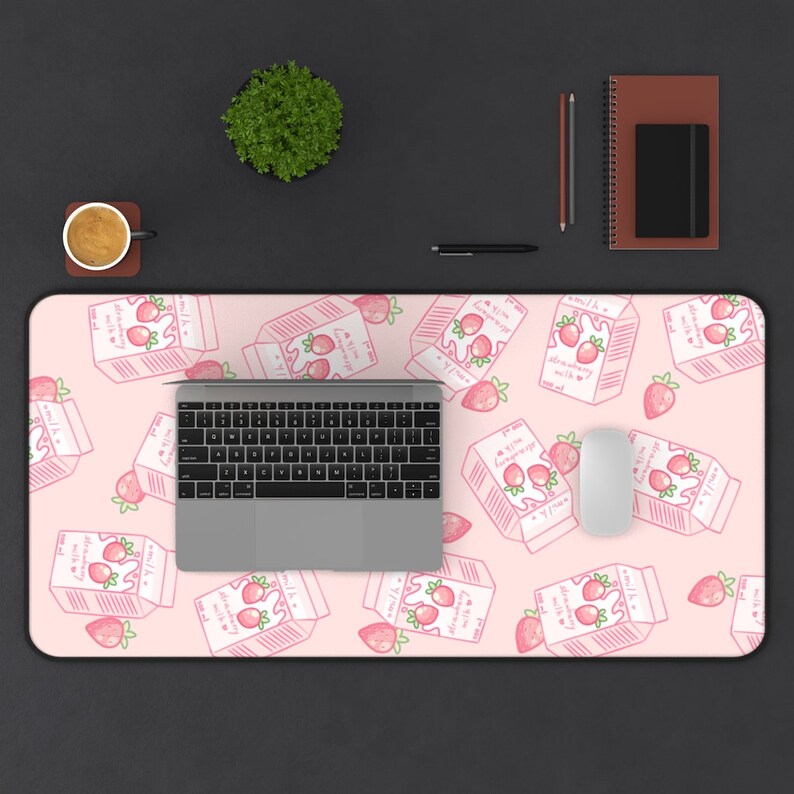 Peut inclure: Tapis de bureau rose avec un motif r&eacute;p&eacute;t&eacute; de cartons de lait &agrave; la fraise en dessin anim&eacute;. Le tapis pr&eacute;sente un ordinateur portable et une souris blanche.