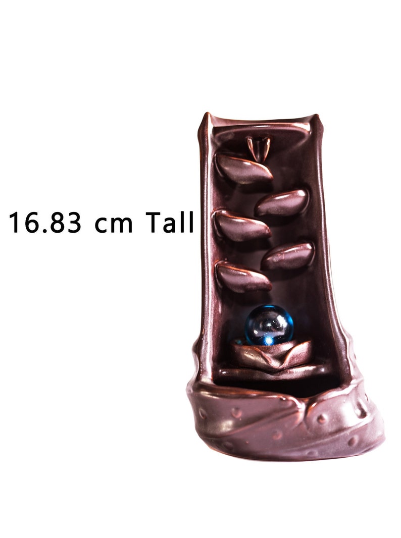 May include: A brown ceramic incense burner shaped like a waterfall with a blue glass ball at the bottom. The burner is 16.83 inches tall.