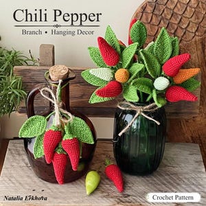 Op de afbeelding: Een gehaakte chilipeper tak hangdecoratie set met rode, oranje en witte pepers met groene bladeren. Het arrangement bevat twee glazen flessen, een bruine en een donkergroene, vastgebonden met touw. Tekst leest Chili Pepper en Crochet Pattern.