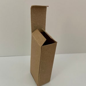May include: A brown cardboard box with a hinged lid, open and angled to the side. The box is empty.
