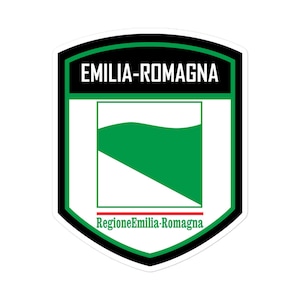 May include: A black and white shield-shaped sticker with the text "EMILIA-ROMAGNA" in white letters. Inside the shield is a white and green flag with a green wave shape. The text "Regione Emilia-Romagna" is written in red and white letters at the bottom of the shield.