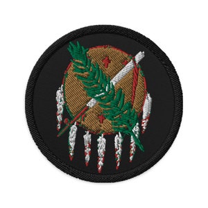 May include: Embroidered patch featuring the state seal of Oklahoma. The seal is a gold shield with a green sprig of willow, a white arrow, and a red tomahawk. The shield is surrounded by a white circle with red and white feathers.