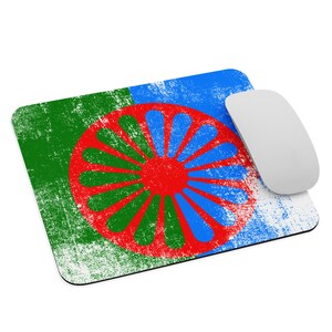 May include: A mouse pad with a distressed design featuring a green, blue, and red wheel with spokes. The wheel is centered on the mouse pad and has a white background.
