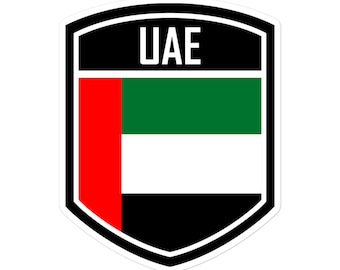 May include: A black and white shield-shaped sticker with the text "UAE" in white letters. The shield features the flag of the United Arab Emirates, with a red vertical stripe on the left, a green horizontal stripe in the middle, and a white horizontal stripe below.