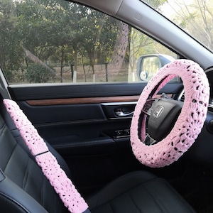 Puede incluir: Funda de volante y cintur&oacute;n de seguridad de ganchillo rosa para un coche. La funda del volante tiene un delicado patr&oacute;n floral.