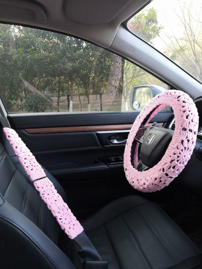 Puede incluir: Funda de volante y cintur&oacute;n de seguridad de ganchillo rosa para un coche. La funda del volante tiene un delicado patr&oacute;n floral.