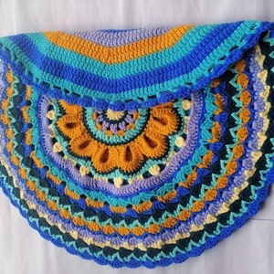 May include: A colorful crocheted half-circle rug with a mandala design in shades of blue, green, yellow, and purple.