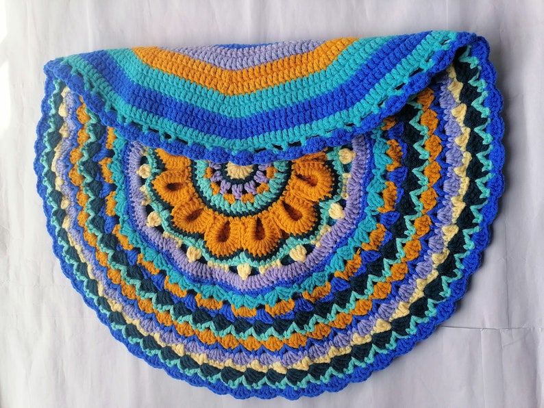 May include: A colorful crocheted half-circle rug with a mandala design in shades of blue, green, yellow, and purple.