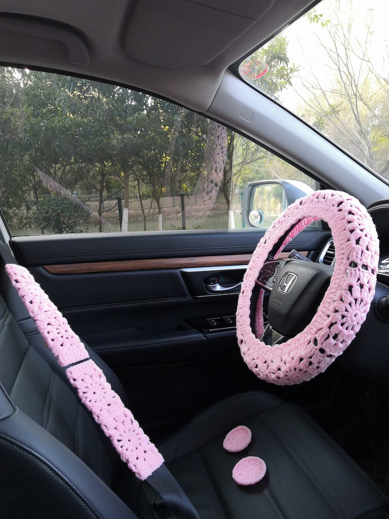 Puede incluir: Funda de volante de crochet rosa, fundas de cintur&oacute;n de seguridad y dos posavasos rosas para el interior de un coche.