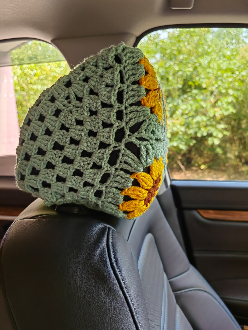 Puede incluir: Un reposacabezas de asiento de coche de ganchillo con un dise&ntilde;o de girasol verde y amarillo. El reposacabezas est&aacute; hecho de un hilo suave y texturizado y est&aacute; dise&ntilde;ado para agregar un toque de comodidad y estilo a cualquier coche.