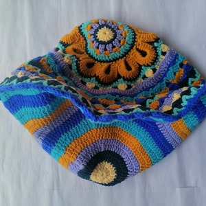 May include: A colorful crocheted blanket with a circular design in shades of blue, orange, yellow, and purple.