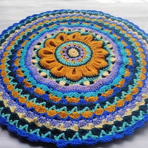 May include: A colorful crocheted round rug with a mandala design in shades of blue, yellow, and purple.