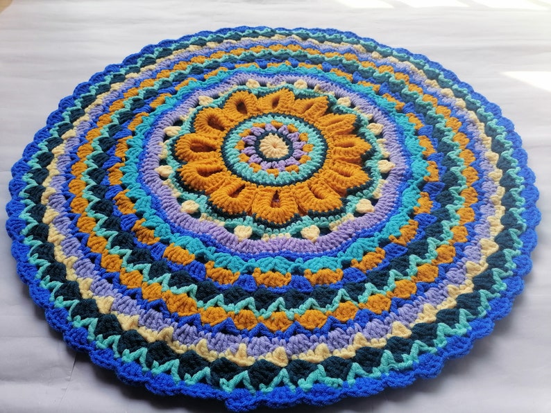 May include: A colorful crocheted round rug with a mandala design in shades of blue, yellow, and purple.