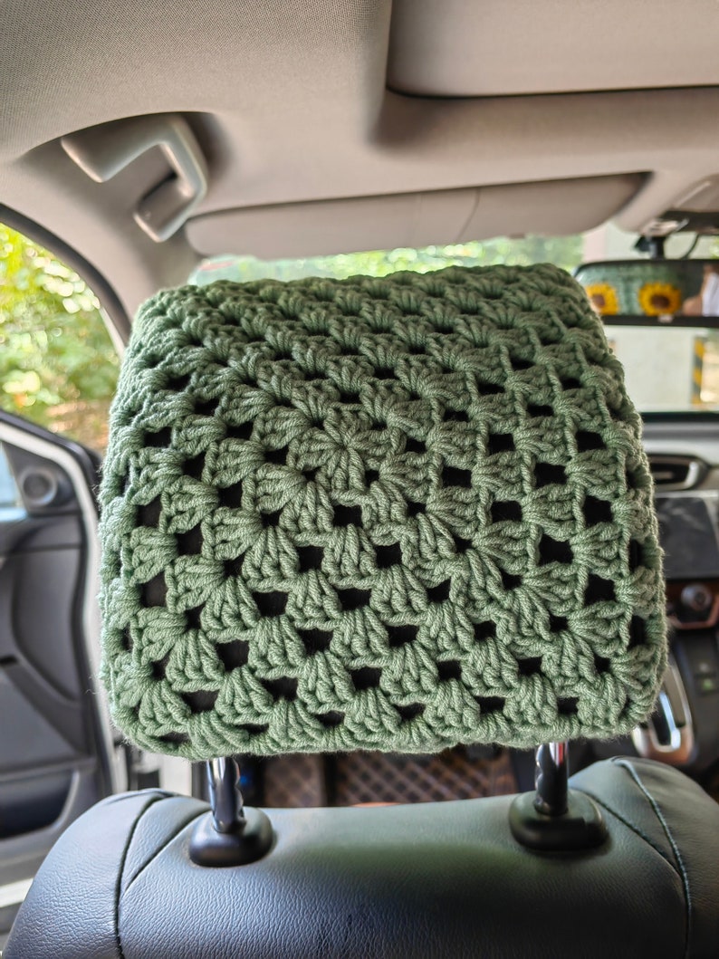 Puede incluir: Un reposacabezas de asiento de coche de ganchillo verde. El reposacabezas est&aacute; hecho con un patr&oacute;n de punto cuadrado.