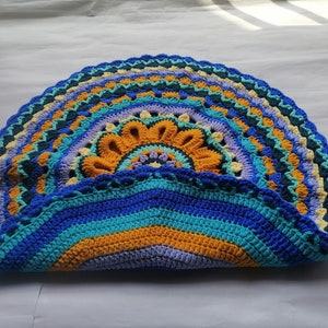 May include: A crocheted half-circle rug with a colorful mandala design in shades of blue, yellow, green, and purple.