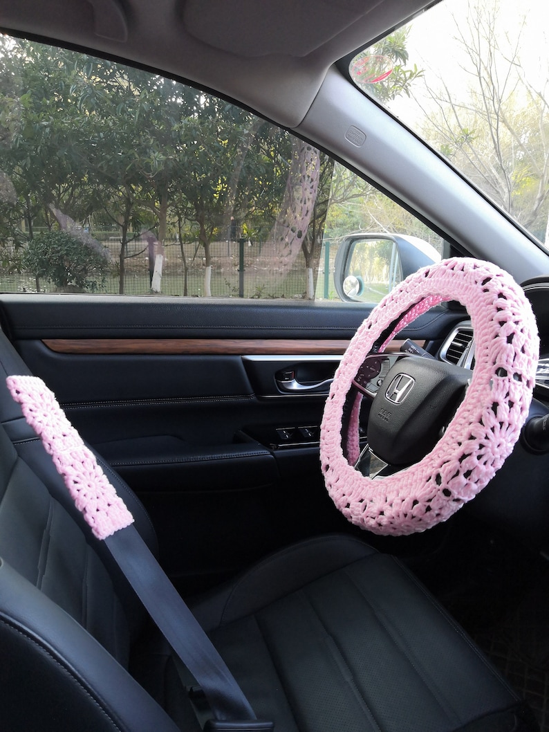 Puede incluir: Funda de volante y cintur&oacute;n de seguridad de ganchillo rosa para un coche. La funda del volante es un dise&ntilde;o grueso de ganchillo con un tejido abierto grande. La funda del cintur&oacute;n de seguridad es un dise&ntilde;o de ganchillo m&aacute;s peque&ntilde;o con un tejido m&aacute;s delicado.