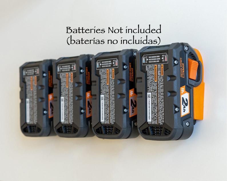 Puede incluir: Una fila de cinco bater&iacute;as de iones de litio de 18 V y 2 Ah de color negro y naranja. Las bater&iacute;as est&aacute;n montadas en una pared blanca. El texto "Batteries Not included" est&aacute; encima de las bater&iacute;as.