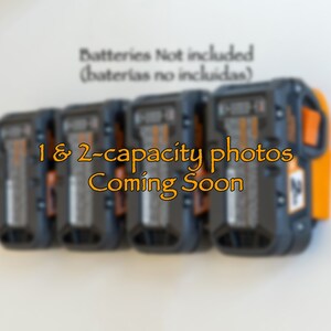 Puede incluir: Soporte de pared para bater&iacute;as de herramientas el&eacute;ctricas, negro y naranja. La imagen muestra varias bater&iacute;as en el soporte. El texto dice "1 & 2-capacity photos Coming Soon" y "Batteries Not included".