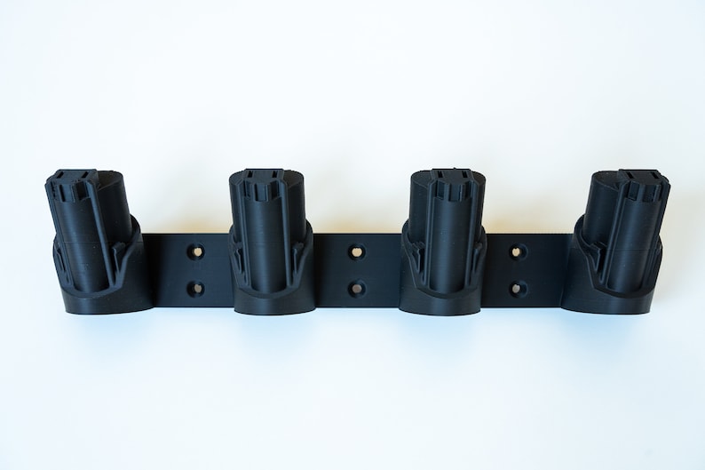 K&ouml;nnte beinhalten: Ein schwarzer, an der Wand montierter Batteriehalter mit vier Schlitzen. Jeder Schlitz ist zur Aufnahme einer Batterie konzipiert. Der Halter hat vorgebohrte L&ouml;cher f&uuml;r die einfache Installation. Er besteht aus einem haltbaren Material.