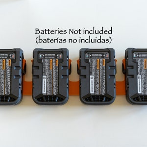 Puede incluir: Cuatro paquetes de bater&iacute;as negros y naranjas montados en un soporte naranja. Cada paquete tiene una etiqueta detallada con texto y un n&uacute;mero de serie. El texto "Batteries Not included" est&aacute; encima de los paquetes.