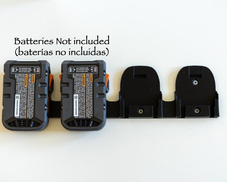 Puede incluir: Un paquete de bater&iacute;as negro y naranja con un soporte negro. El paquete de bater&iacute;as tiene una etiqueta con texto y est&aacute; conectado a un soporte negro con dos ranuras. El texto "Batteries Not included" est&aacute; encima del paquete de bater&iacute;as.