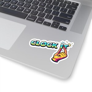 May include: A sticker with the words "CLOCK IT" in a colorful, stylized font. The image includes a hand pointing at the word "IT" with a starburst effect. The sticker is placed on a laptop.