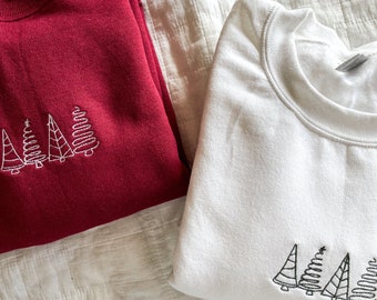 May include: Two sweatshirts with embroidered Christmas trees. One sweatshirt is red and the other is white.