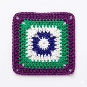 Puede incluir: Una pieza cuadrada de ganchillo hecha a mano con un diseño floral. El centro presenta una forma de flor azul rodeada de blanco. Bandas verdes y moradas enmarcan el diseño. El borde exterior es de color morado liso. La pieza es probablemente un artículo decorativo o parte de un proyecto más grande.