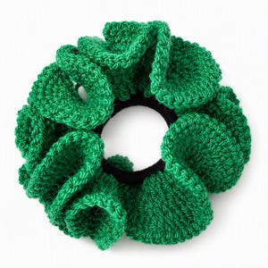 Puede incluir: Un coletero de ganchillo en color verde vibrante con un diseño texturizado y con volantes. El accesorio está construido con una banda elástica negra circular y flexible en el centro, rodeada de densos bucles de hilo verde cosidos a mano.