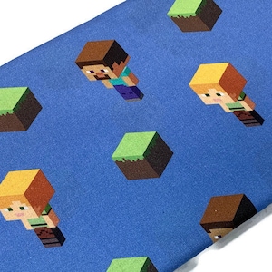 May include: Blue fabric with a repeating pattern of Minecraft characters and green blocks. The characters are Steve and Alex, and the blocks are grass blocks.