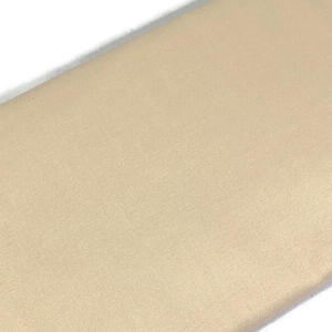 May include: A close-up of a smooth, light beige fabric. The fabric has a subtle sheen and a slightly textured surface.