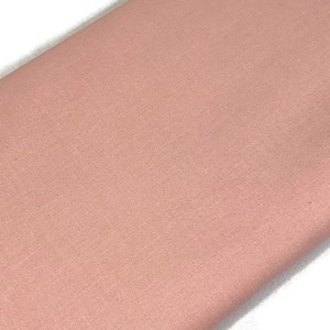 May include: A solid piece of fabric in a light pink color. The fabric has a smooth, even texture.
