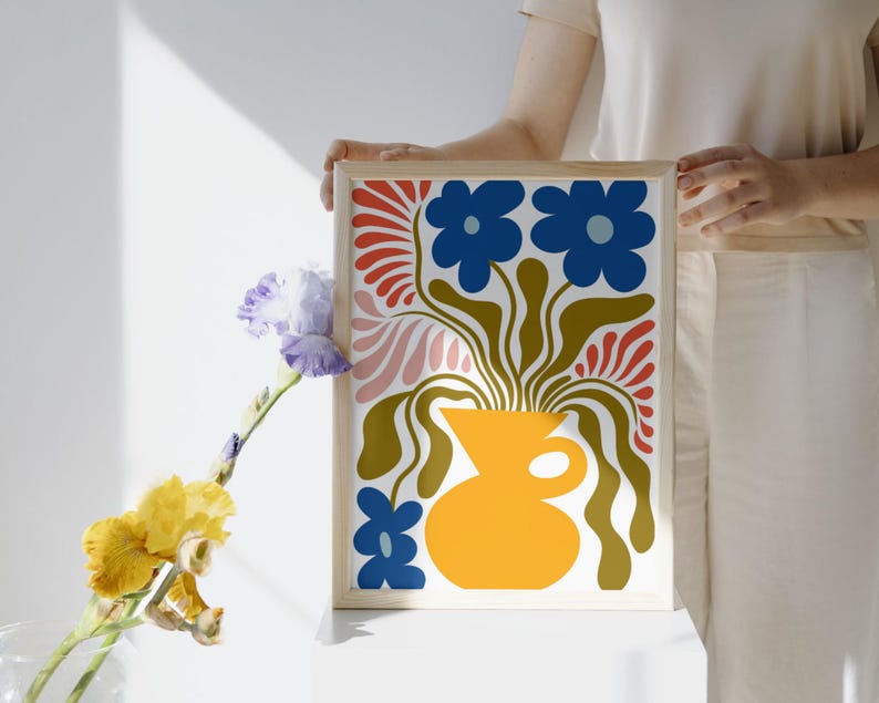 Puede incluir: Una impresi&oacute;n floral abstracta colorida con flores azules en un jarr&oacute;n amarillo. La impresi&oacute;n est&aacute; enmarcada en un marco de madera claro.