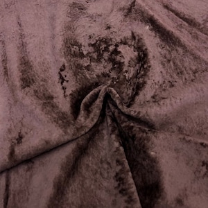 Può includere: Una pelle di pelliccia sintetica marrone con una texture morbida e soffice. La pelliccia è piegata al centro, rivelando il lato inferiore della pelle.