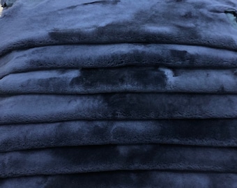 Puede incluir: Una pila de pieles de oveja azul oscuro, mostrando la textura suave y peluda de la piel.