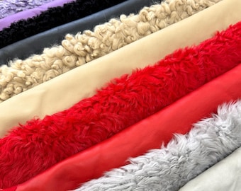 Puede incluir: Una colección de ocho muestras de tela de piel sintética en varios colores, incluyendo morado, negro, beige, marrón claro, rojo, gris y blanco.