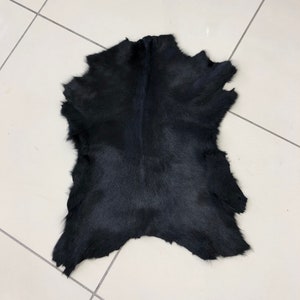 May include: A black cowhide rug with a natural, slightly textured surface.