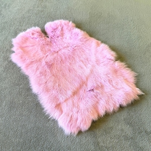 May include: A soft, pink fur rug with a fluffy texture.