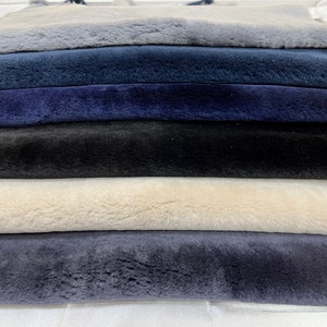 May include: A stack of six faux fur fabric swatches in various shades of blue, black, and white. The fabric is soft and plush.