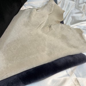 May include: A close-up of two fabric swatches. One is a light gray faux fur fabric and the other is a dark gray velvet fabric.