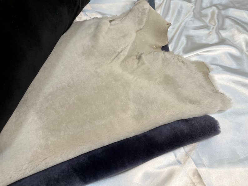 May include: A close-up of two fabric swatches. One is a light gray faux fur fabric and the other is a dark gray velvet fabric.